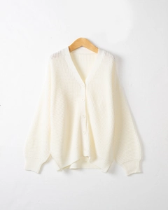 Dettaglio della trama a nido d'ape e bottoni abbinati su un cardigan bianco con scollo a V