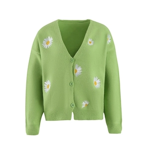 Detailed close-up of daisy embroidery and buttons on a green knit cardigan