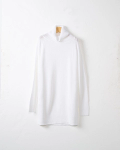 Close-up of white turtleneck knit dress showing vertical ribbed texture and drop shoulder