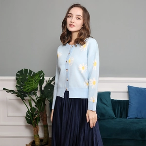 Close-up of light blue cardigan featuring white daisy embroidery and ribbed cuffs
