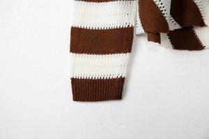 Detail of brown and white striped knit sweater with hollow out texture and ribbed cuffs