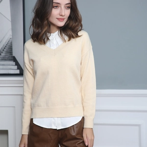 Women's V-neck beige knit sweater layered over a white shirt for a casual autumn look