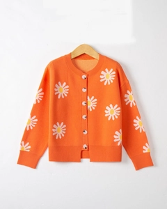 Close-up of bright orange knitted cardigan with white daisy embroidery and ribbed cuffs