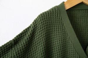 Dettaglio della trama in maglia a nido d'ape verde scuro e del colletto a coste su gruccia