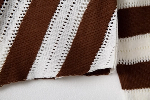 Detail of V-neck striped knit sweater with pointelle stitching in brown and white