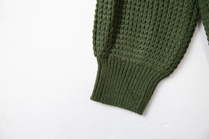 Dettaglio di polsini di maglione in maglia a nido d'ape verde scuro con bordo a coste