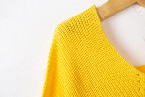 Detailed close-up of thick chunky knit texture and V-neckline on a yellow sweater