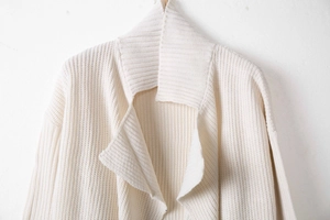 Detail of cream chunky knit cardigan featuring lapel collar and vertical ribbed texture