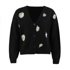 Detail of white daisy embroidery and ribbed cuffs on black knit cardigan sweater
