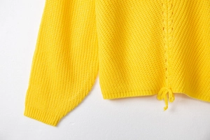 Detail of yellow chunky knit sweater showing V-shaped texture and adjustable drawstring hem