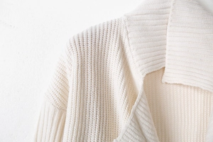 Detail of the thick vertical ribbed knit texture on a cream-colored lapel cardigan sweater