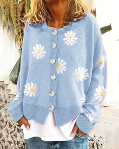 Detailed close-up of light blue knit cardigan with white daisy floral embroidery and buttons