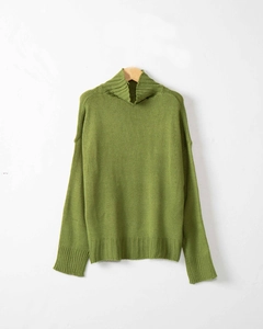 Dettaglio di maglione a maglia grossa verde erba con collo a lupetto e texture a coste