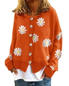 Close-up of orange knit cardigan featuring white daisy embroidery and pearl buttons