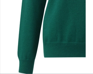 Detailed macro view of dark green ribbed knit cuffs and hem texture on women's sweater