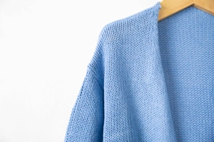 Close-up of thick knit texture and shoulder detail on a light blue long cardigan