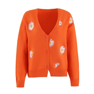 Detail of orange knit cardigan with white daisy embroidery and three buttons closure