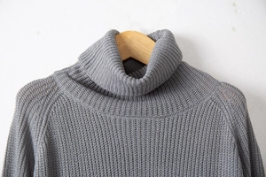 Close-up of grey knit sweater showing chunky vertical rib texture and turtleneck detail
