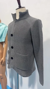 Detail view of dark grey waffle-knit cardigan jacket with buttons and front pockets