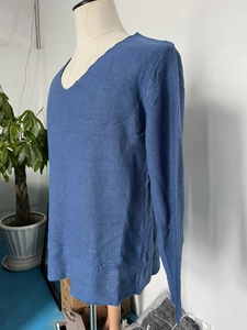 Close-up of a blue V-neck pullover sweater showing the detailed fine-knit texture