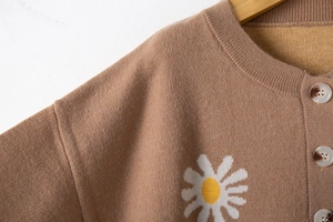 Detail of knit cardigan collar with daisy embroidery and marble texture buttons