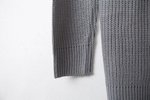 Detailed macro view of the grey knit sweater featuring ribbed cuff and soft texture