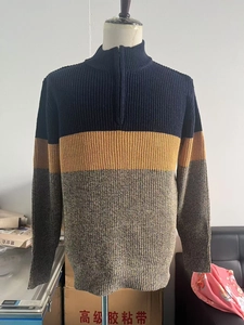Detail of men's knitted sweater with navy, yellow, and grey patchwork and half-zip collar