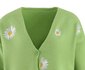 Detailed view of daisy embroidery and buttons on green knitted cardigan sweater