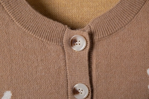 Detail of camel knit cardigan showing ribbed round neck and marble texture buttons