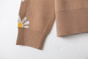 Macro shot of knitted daisy pattern and ribbed cuffs on camel brown knit cardigan jacket