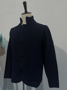 Detail of navy blue waffle knit cardigan with stand collar and three black buttons