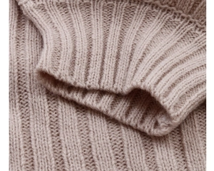 Macro shot of thick ribbed knit texture and ribbed cuffs on a beige winter sweater
