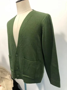 Detailed close-up of dark green men's cardigan featuring ribbed texture and v-neck button design
