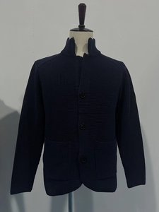 Detail of dark blue knit cardigan featuring waffle texture and standing collar with buttons