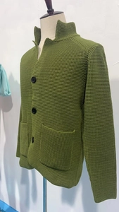 Close-up of grass green waffle knit texture with black buttons on a men's cardigan