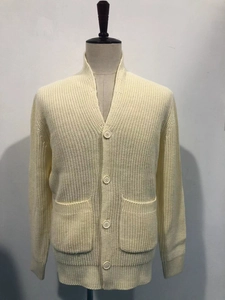 Detailed close-up of beige ribbed knit cardigan with button closure and large front pockets