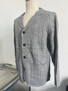 Detail of grey cable-knit cardigan featuring lapel collar, buttons and side pockets
