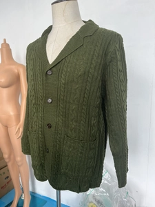 Detail of dark green cable knit cardigan with notch lapel and brown buttons