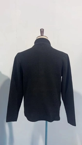 Detail view of the back of a black waffle knit sweater with ribbed cuffs and hemline