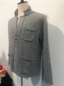 Detail der dunkelgrauen Strickjacke mit Holzknöpfen und funktionellen aufgesetzten Taschen