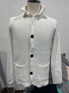 Detail shot of white waffle knit texture and black buttons on a men's stand collar cardigan