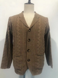 Detail of brown cable-knit cardigan featuring lapel collar and large front pockets