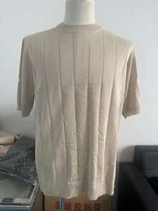 Close-up of beige short-sleeve knit shirt featuring vertical ribbed texture and crew neck