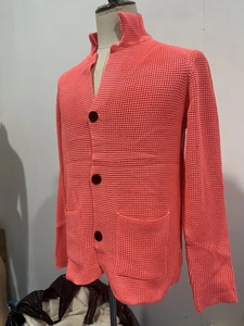 Detail of coral waffle knit cardigan featuring stand collar and large black buttons