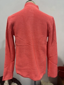 Detail of coral orange waffle knit fabric and ribbed stand collar on a men's cardigan
