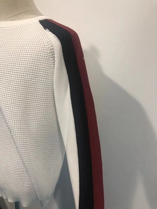 Gros plan détaillé du pull en maille filet blanche avec rayures rouges et bleues