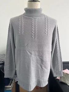 Detail of grey cable knit pattern and ribbed cuffs on men's turtleneck sweater