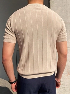 Detail view of the ribbed texture and seamless shoulder line of a beige knit T-shirt