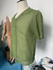 Close-up of green knit mesh texture and button detail on short sleeve shirt