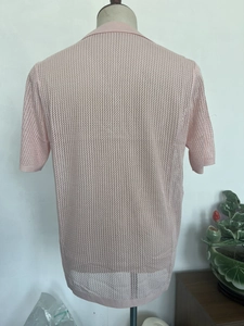 Close-up of pink knit hollow texture on short sleeve men's polo shirt fabric detail